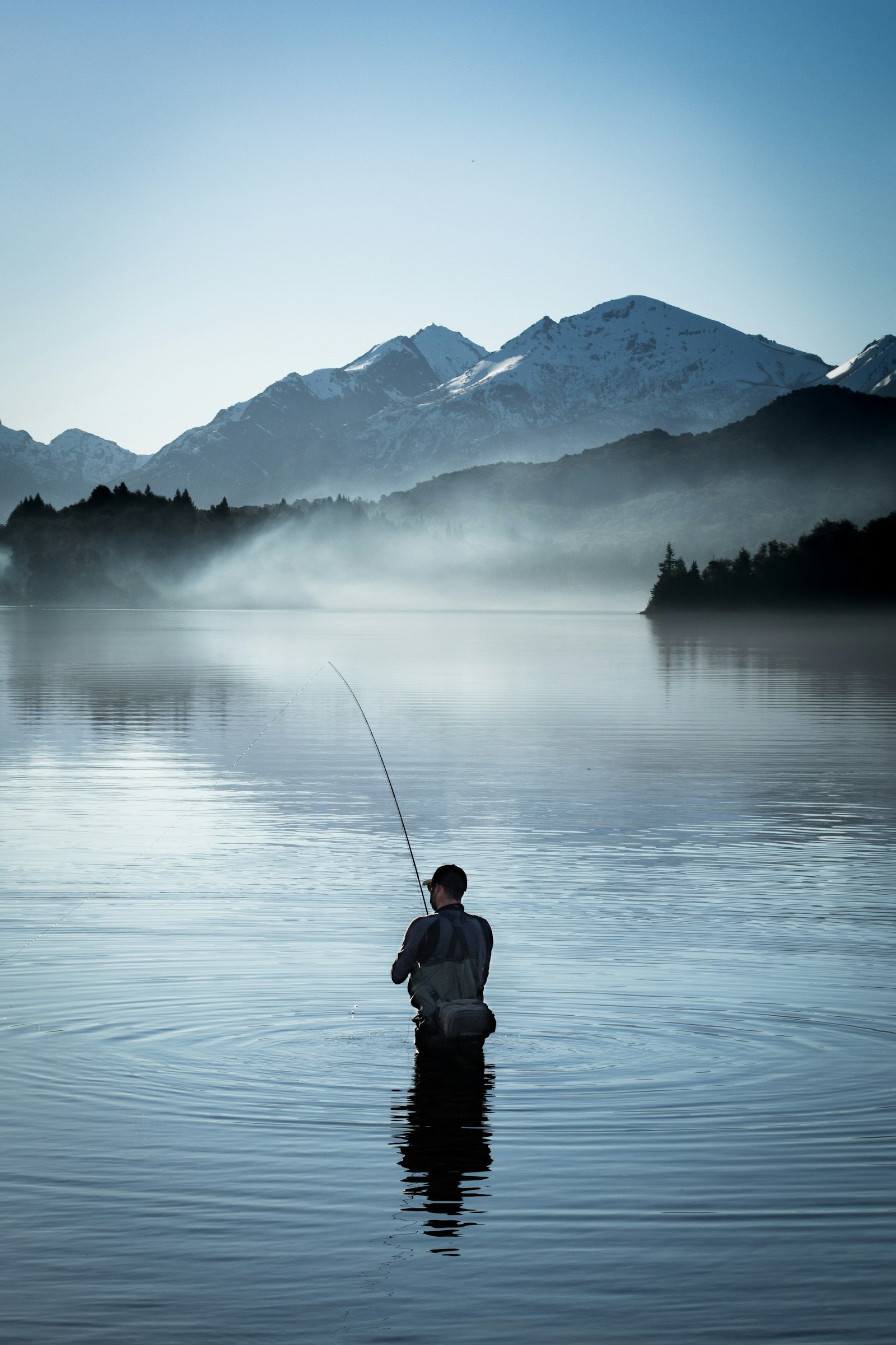 Angler casting a fishing rod at golden hour